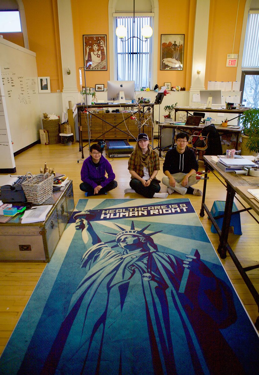 Invo team members having fun displaying their 'Healthcare is a Human Right' large-scale print-out on the floor